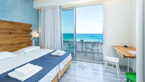 A hotel room with a large bed, a desk, and a view of the ocean. - Meltemi Coast Suites (Rethymno)