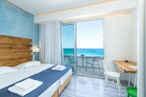 Habitación de hotel con una cama grande, un escritorio y vista al océano.