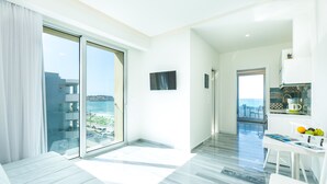 A modern hotel room with a balcony, a dining area, and a view of the sea. - Meltemi Coast Suites (Rethymno)