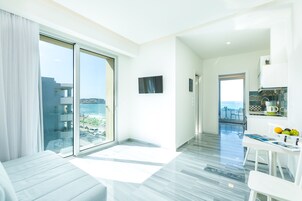 Una habitación de hotel moderna con balcón, zona de comedor y vistas al mar.