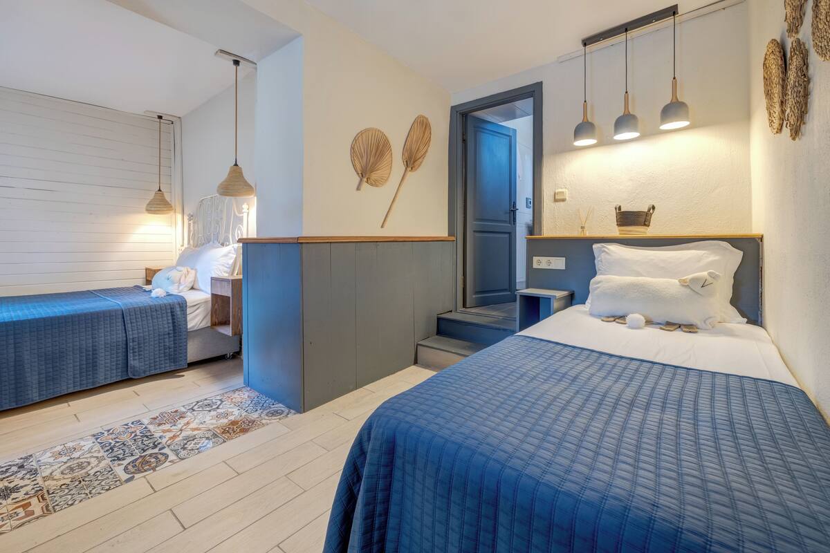 A bedroom with two beds, a patterned rug, and a staircase leading to an upper level.
