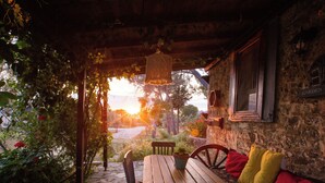 A rustic outdoor seating area with a wooden table and benches, surrounded by greenery and a stone wall. - Aral Tatil Ciftligi (Bozcaada)