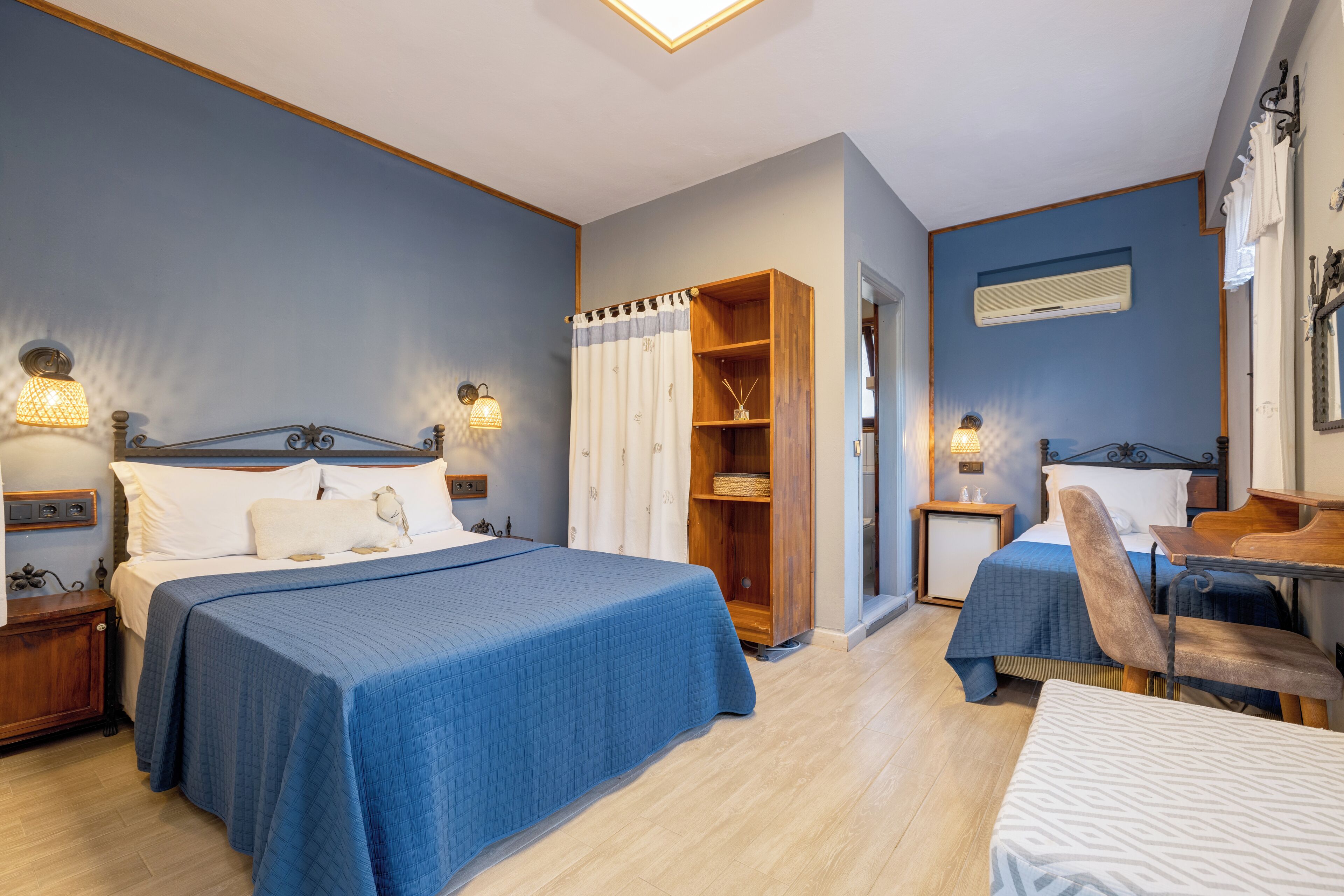 A bedroom with a large bed, bedside tables, a wooden wardrobe, a chair, and a desk.