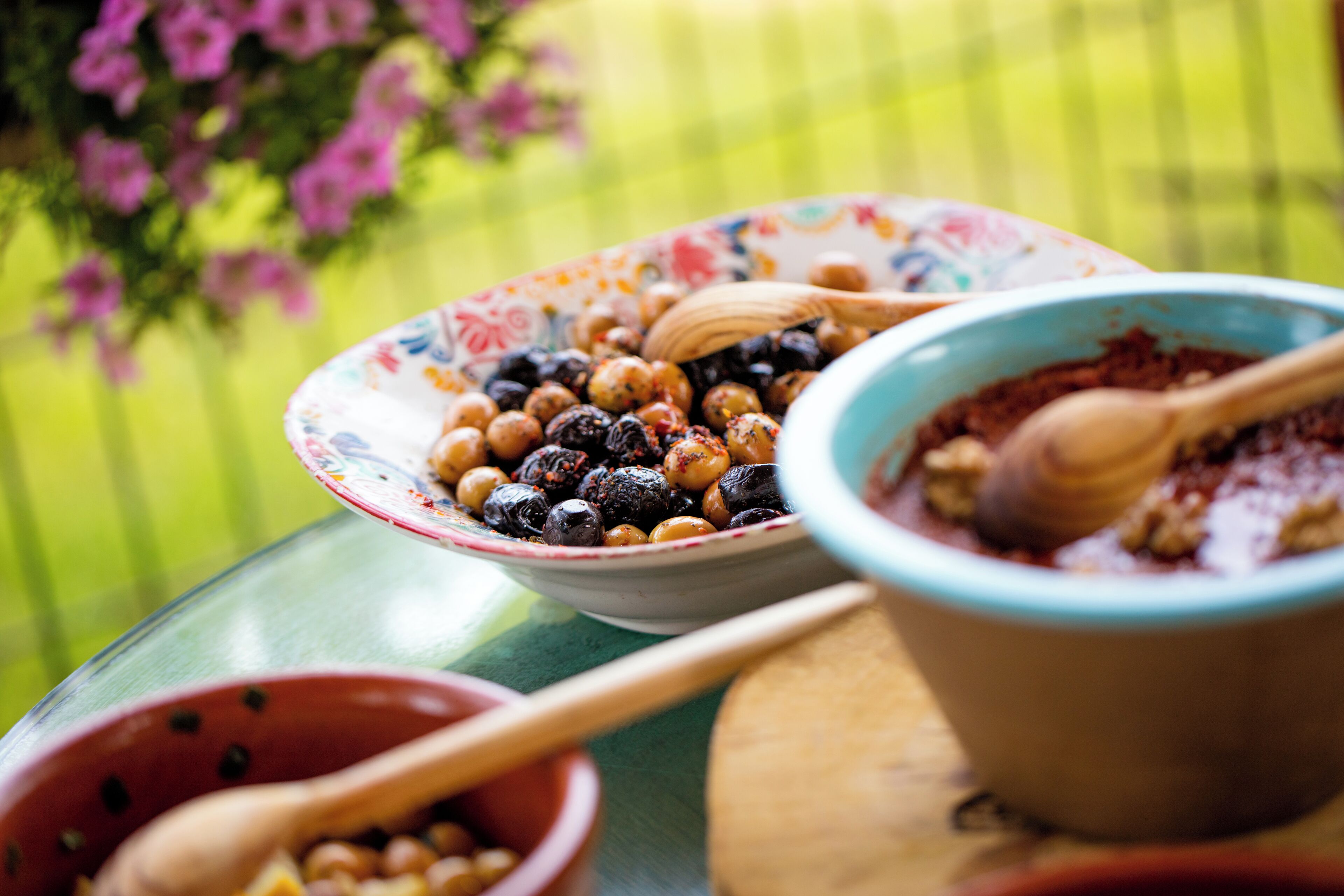 A table with bowls of food and wooden spoons.