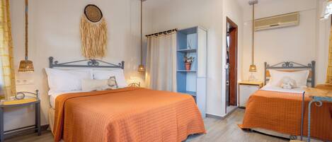 A bedroom with two beds, a bedside table with a lamp, a wardrobe, and a wall-mounted air conditioner.