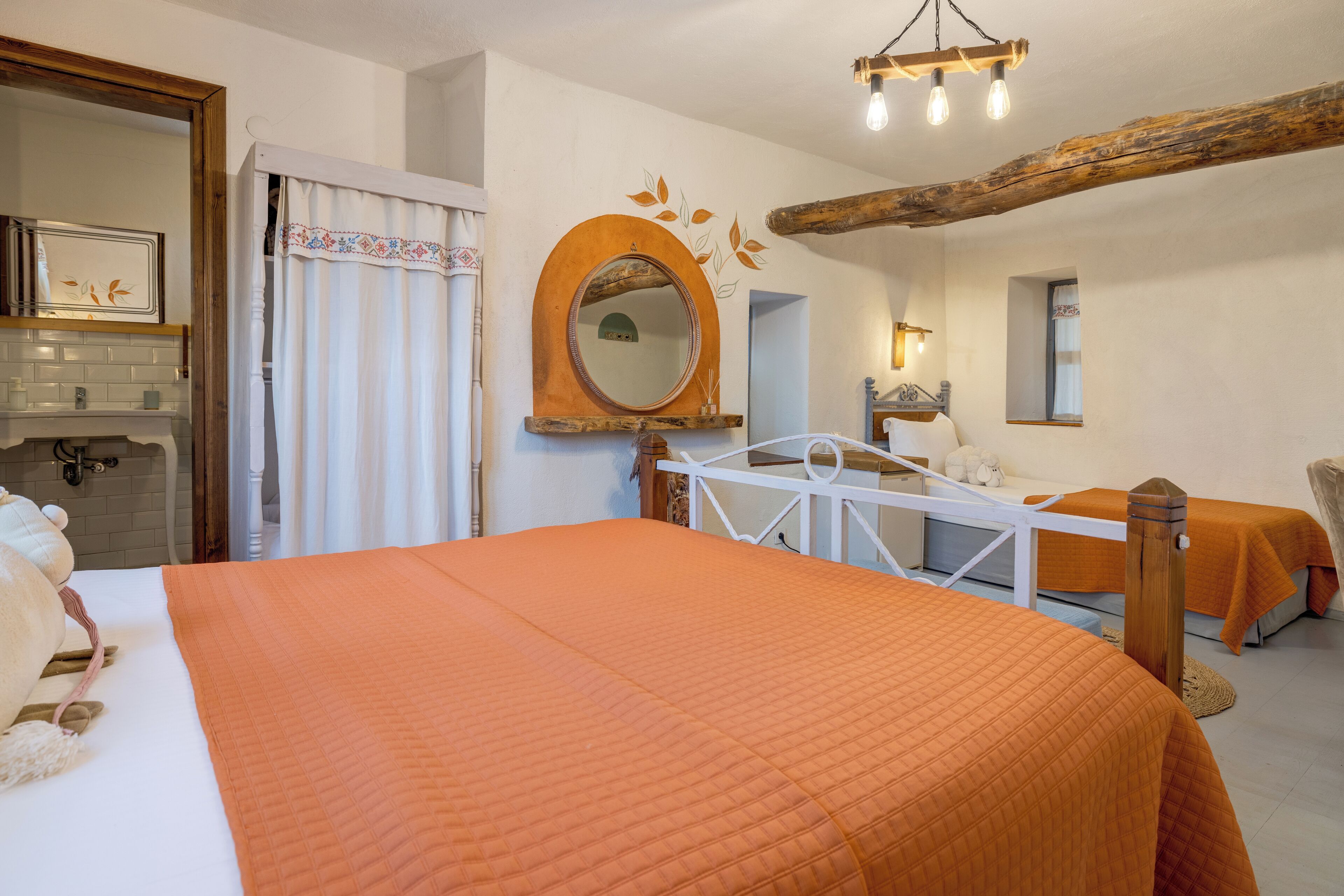Une chambre d’hôtel avec un grand lit, deux tables de chevet, un miroir et un plafond avec une poutre en bois.