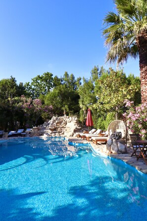 Una piscina al aire libre, sombrillas, sillones reclinables de piscina