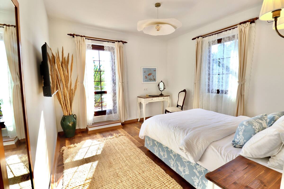 A bedroom with a bed, bedside table, and a desk with a chair.
