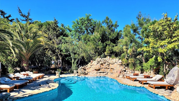 Una piscina con sillas de descanso y un telón de fondo rocoso.