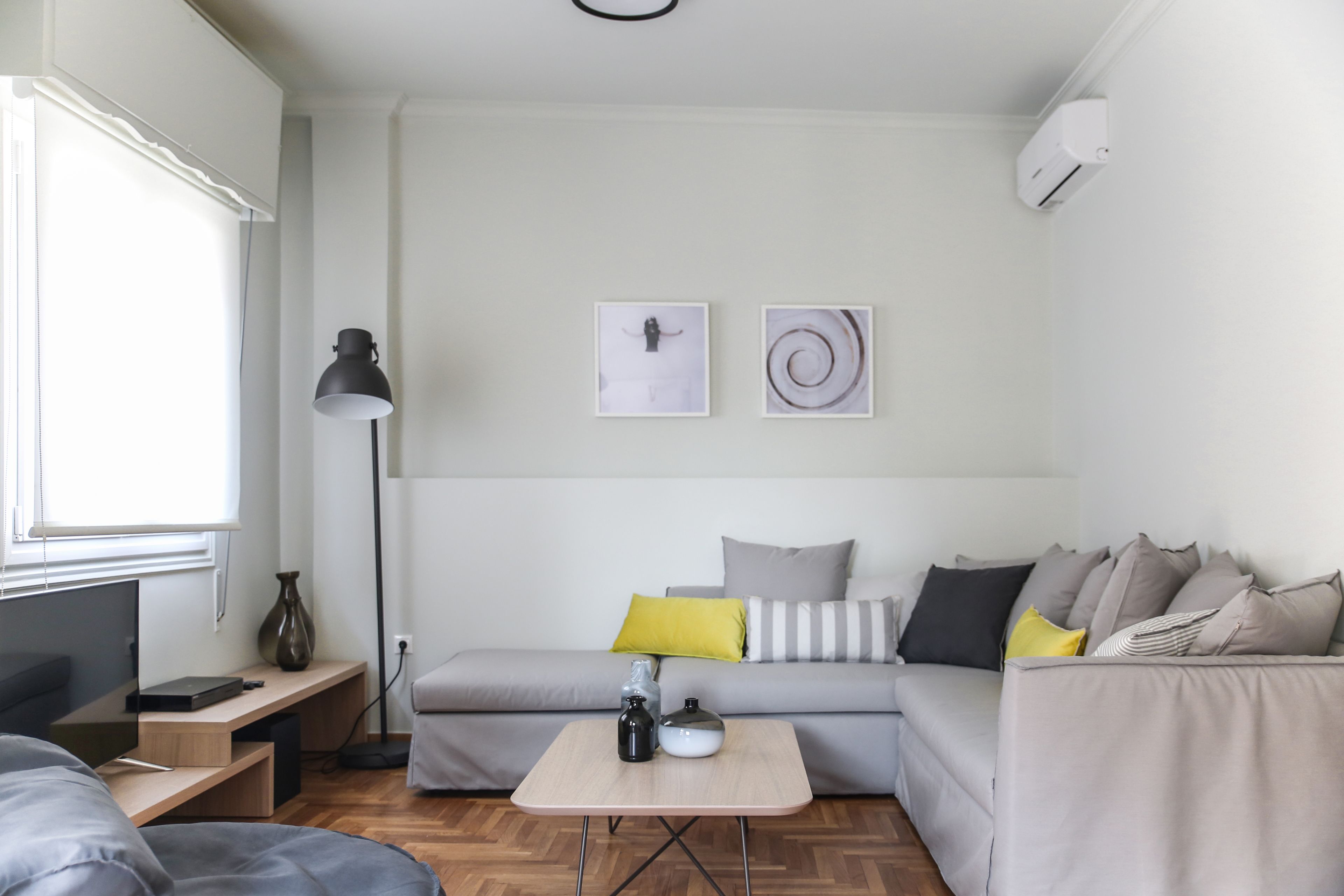 Un salon moderne avec un canapé, une petite table, une lampe et des œuvres d’art accrochées au mur.