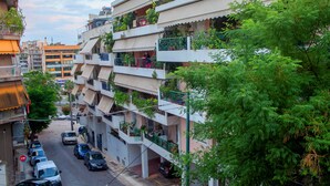 Un edificio residencial de varios pisos con balcones, coches aparcados y zonas verdes.