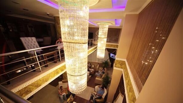 A hotel lobby with a high ceiling, large chandeliers, a seating area, and a view of the upper floor. - Simper Hotel (Istanbul)