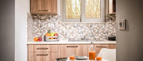Cocina con armarios de madera, salpicadero de azulejos, ventana con vista a bambú y alimentos para el desayuno sobre la encimera.