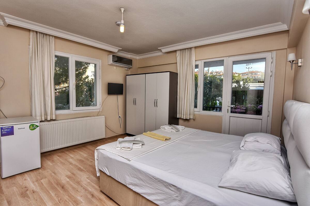 Une chambre d’hôtel avec un lit, une armoire, un radiateur, une télévision et une fenêtre avec des rideaux.