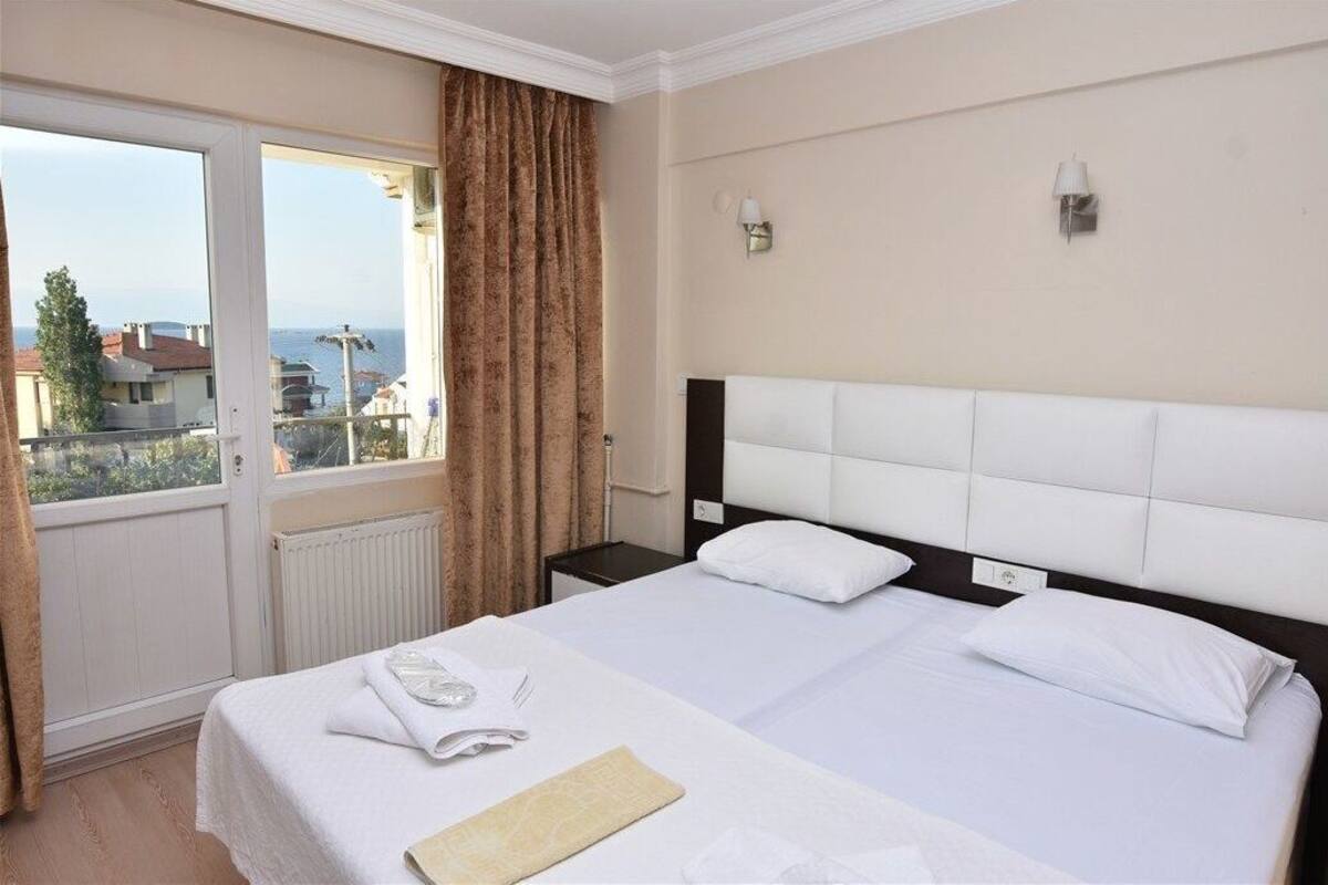 Une chambre d’hôtel avec un grand lit, une fenêtre avec des rideaux, un radiateur et deux appliques murales.