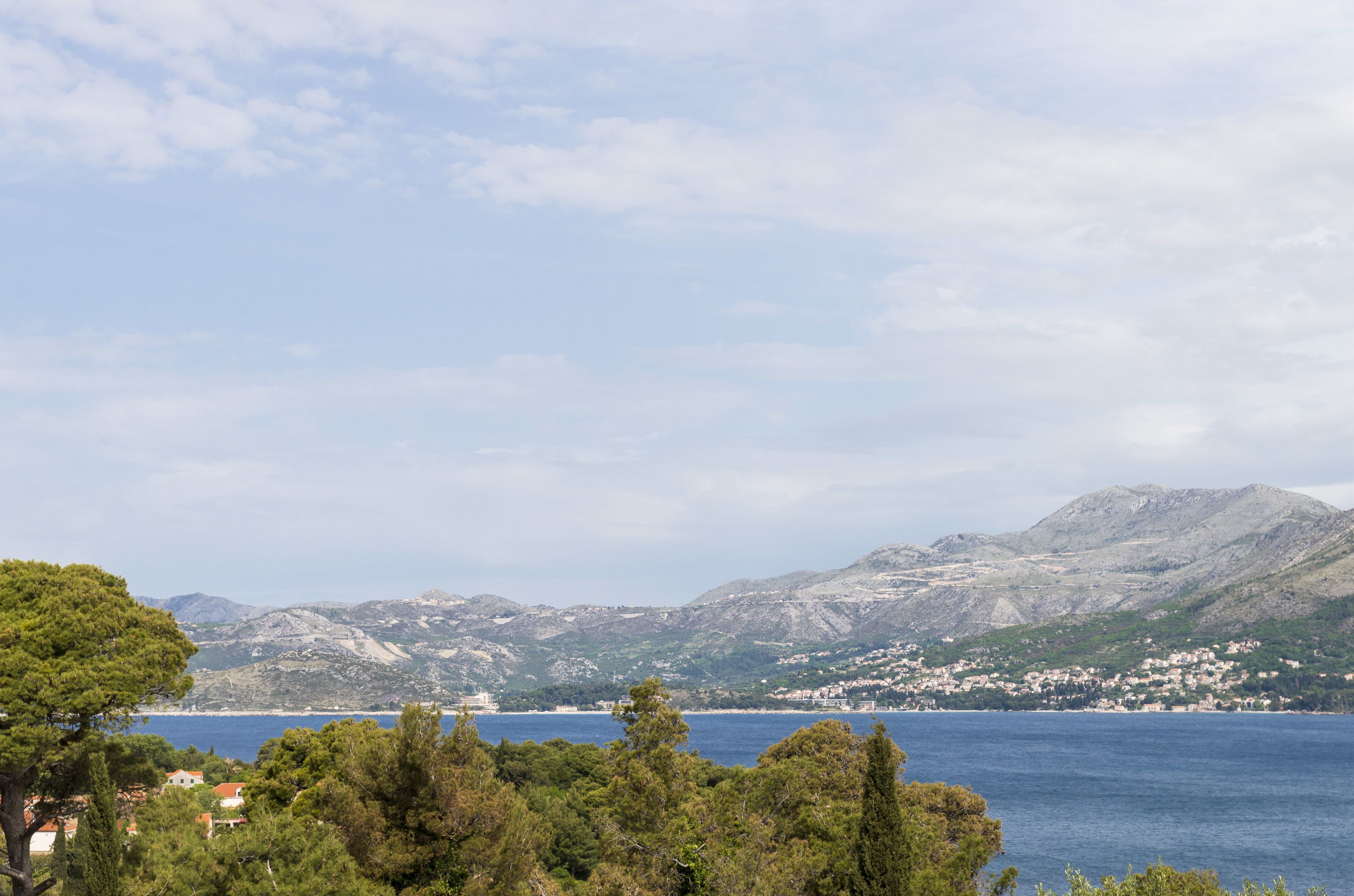 Un paysage côtier avec des montagnes, un ciel dégagé et une étendue d’eau.