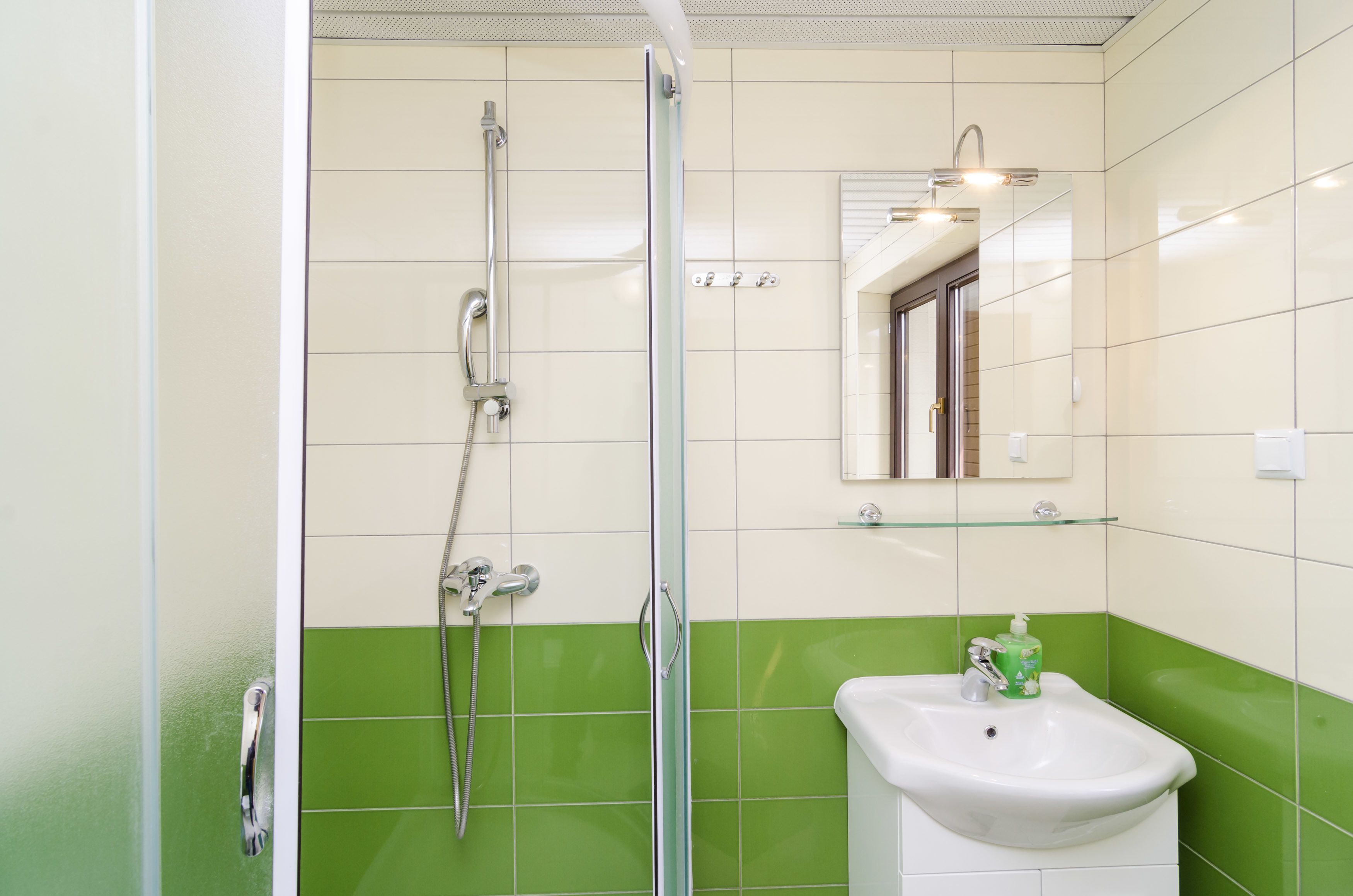 Un baño con ducha, lavamanos y espejo.