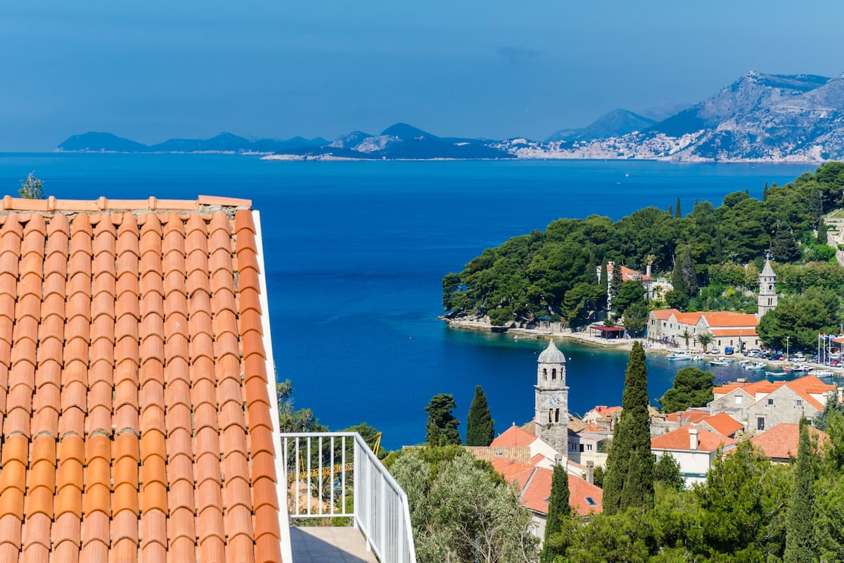 A coastal town with terracotta roofs, a prominent church, and a clear view of the sea.