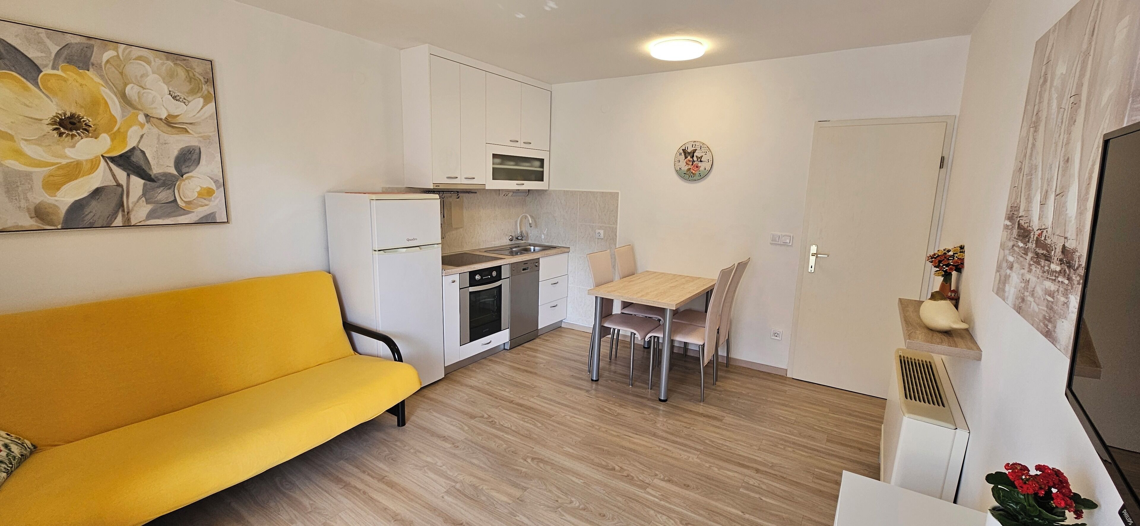 A compact living space with a kitchenette, a dining area, and a sofa.