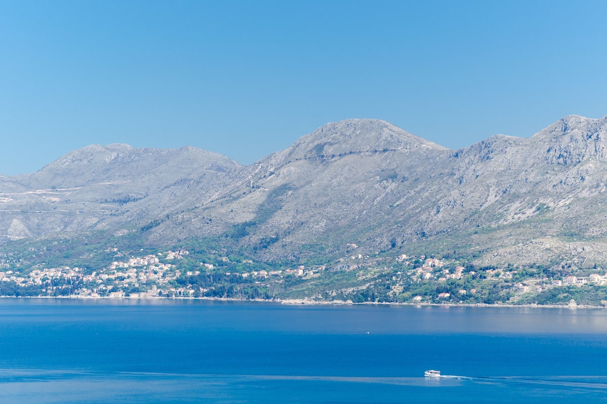 A coastal town with a mountain backdrop and a clear blue sea.
