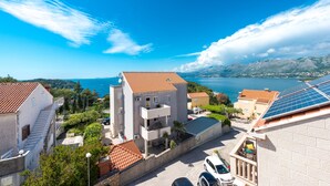 A coastal residential area with buildings, a clear blue sky, and a view of the sea. - Cina Apartments (Konavle)