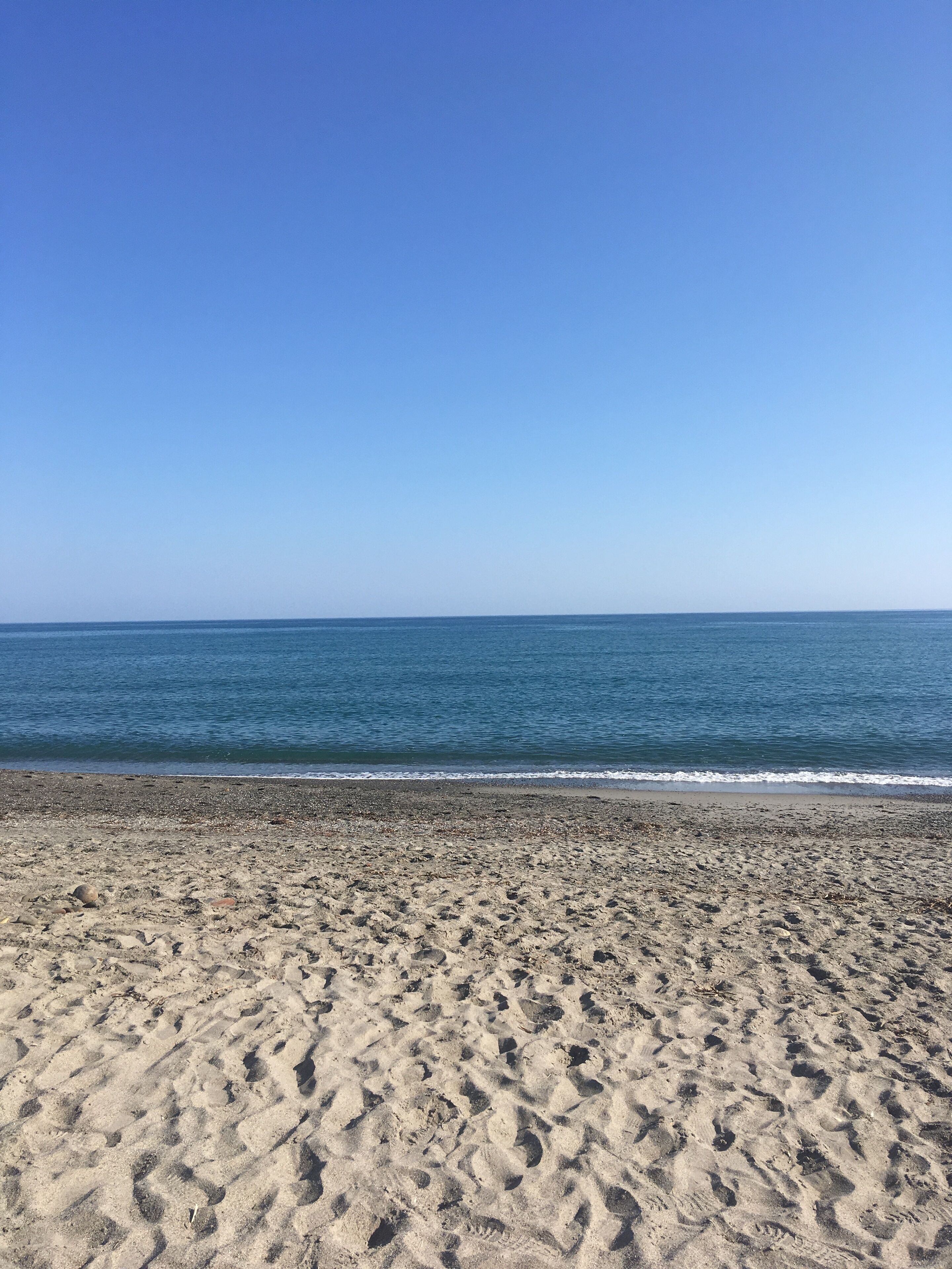 A beach with a clear sky and calm sea.