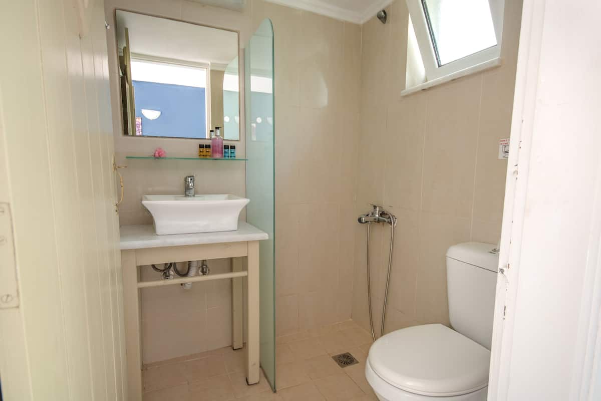 Et badeværelse med hvid vask, spejl og toilet.