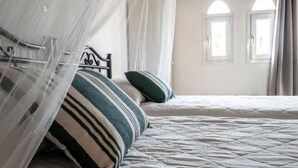 Un dormitorio con cama, dosel y dos ventanas.