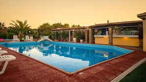 Una piscina con sillones de descanso, un bar y un restaurante.