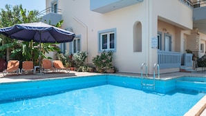 Una piscina al aire libre, sombrillas, sillones reclinables de piscina
