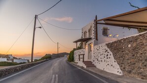 Une route côtière bordée d’un mur de pierres et d’un bâtiment blanc avec des marches menant à une porte.