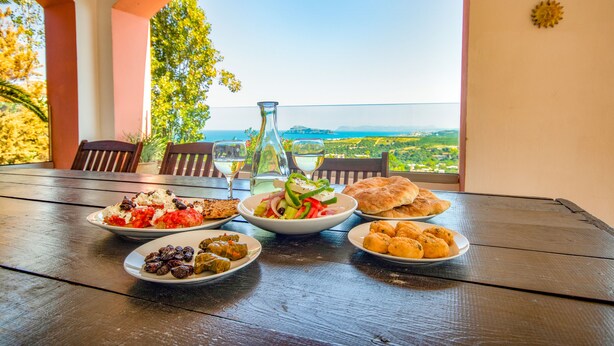 A table with various dishes and a view of a coastal landscape.