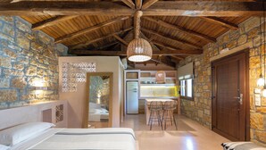 Une pièce confortable avec un lit, un bureau avec des chaises, un mur en pierre et un plafond en bois.
