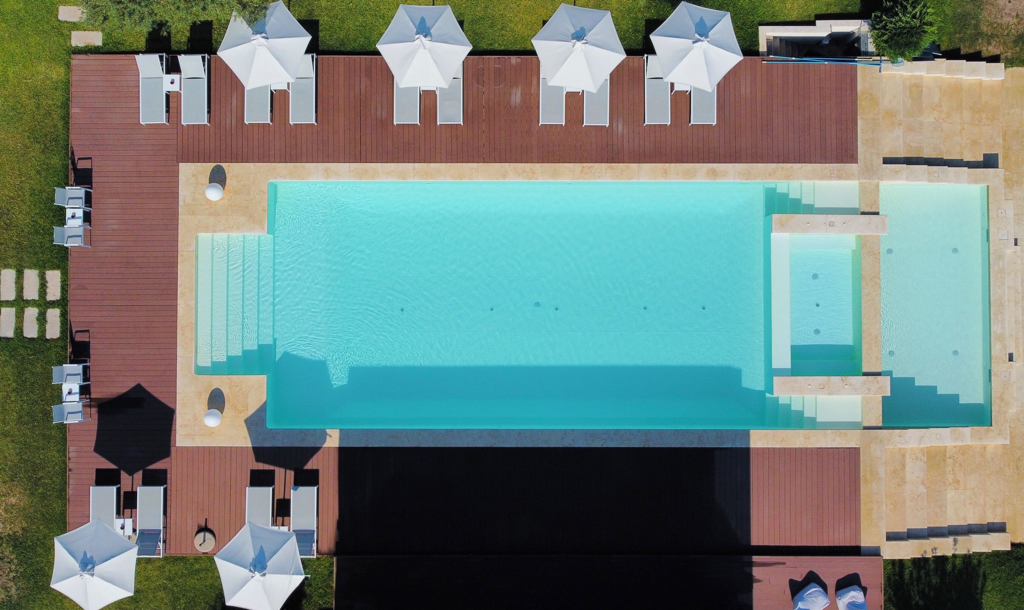 An aerial view of a resort with a swimming pool, sun loungers, and a deck area.