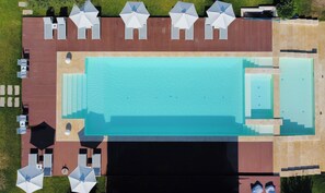 Vista aèria d'un complex turístic amb piscina, gandules i zona de solàrium.