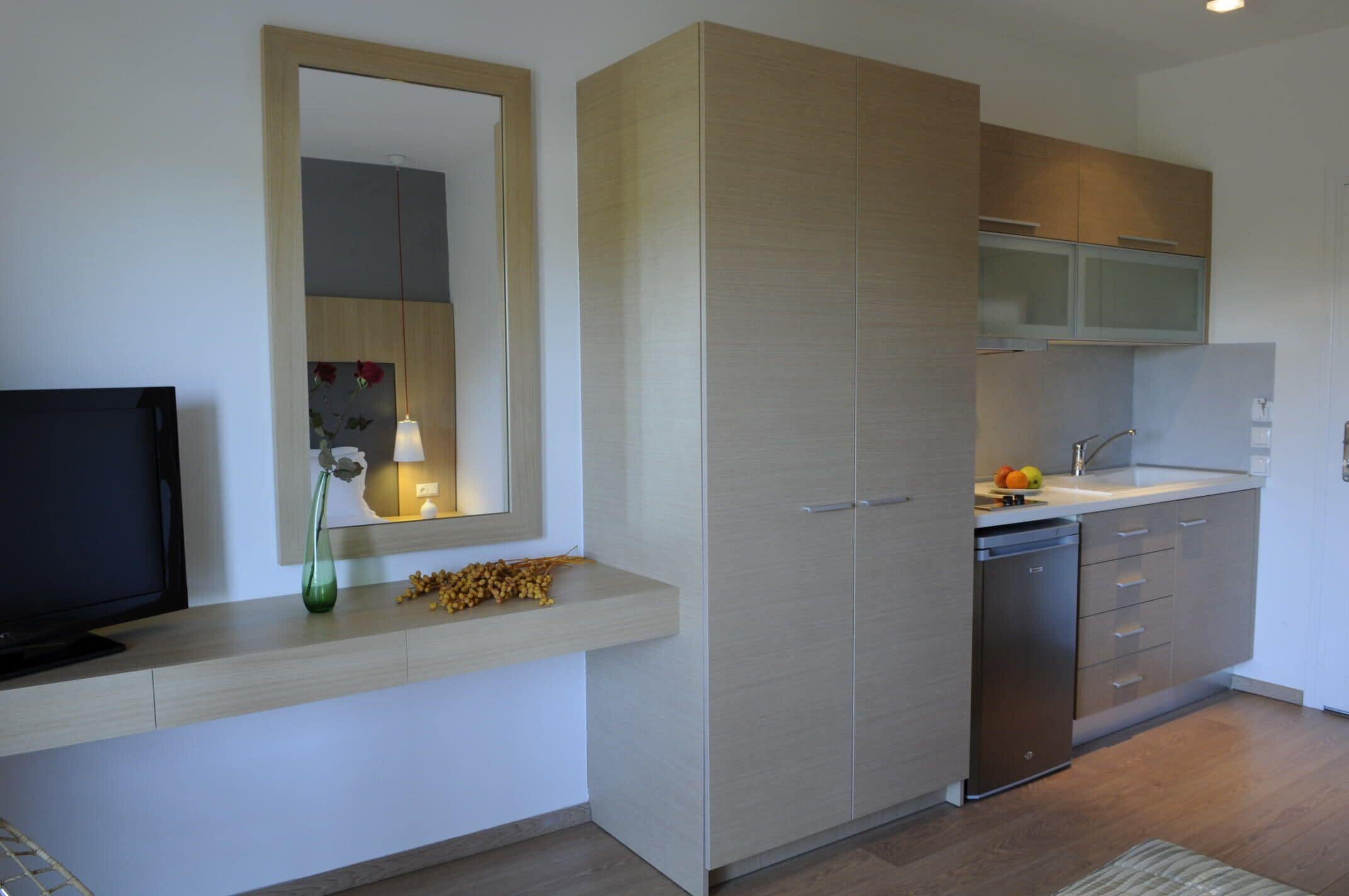 A modern kitchen with a built-in dishwasher, a mirror above the counter, and a television on the left.