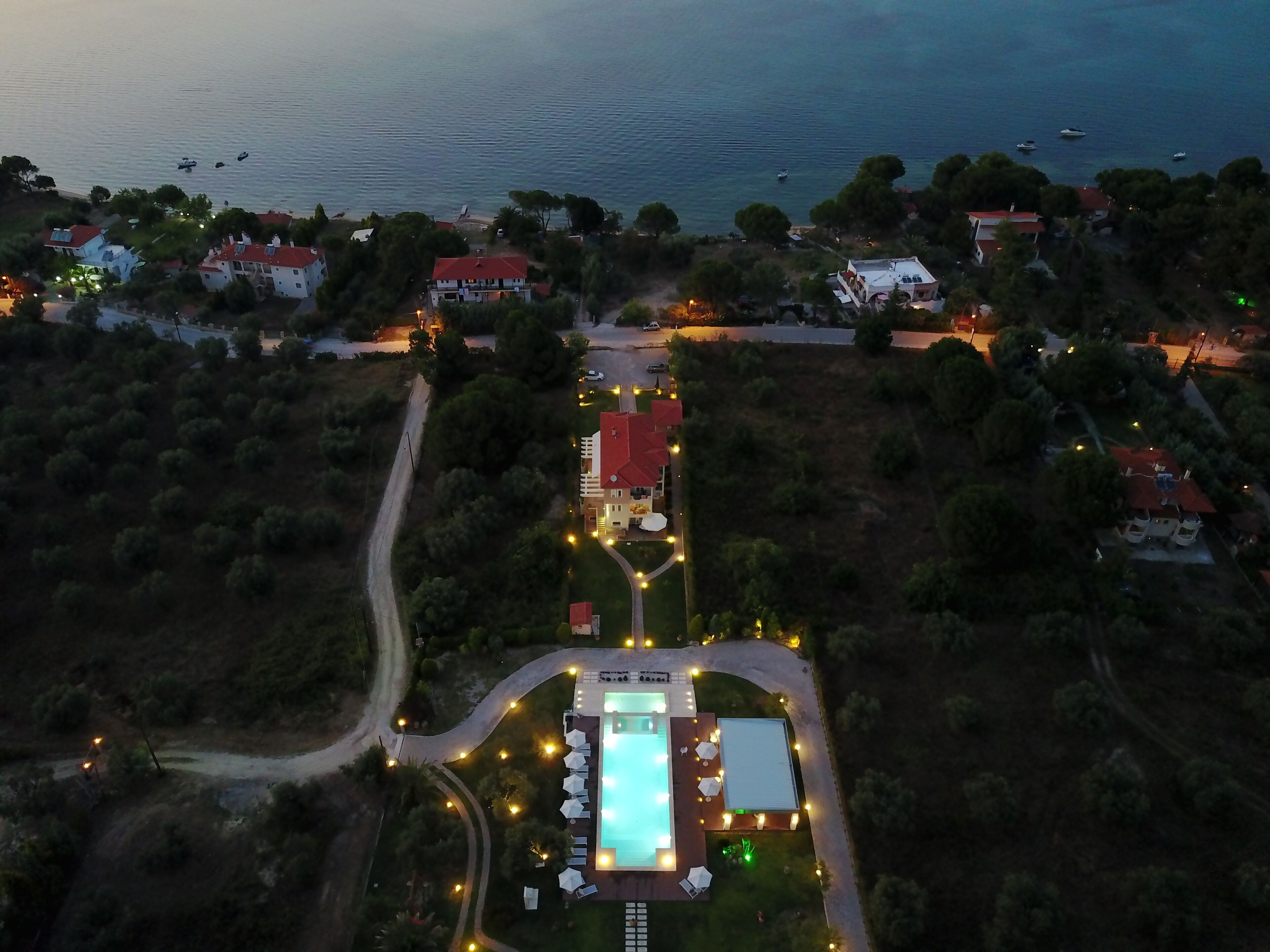 Vue aérienne d’une propriété située sur la côte, avec une piscine, des allées et une végétation luxuriante.
