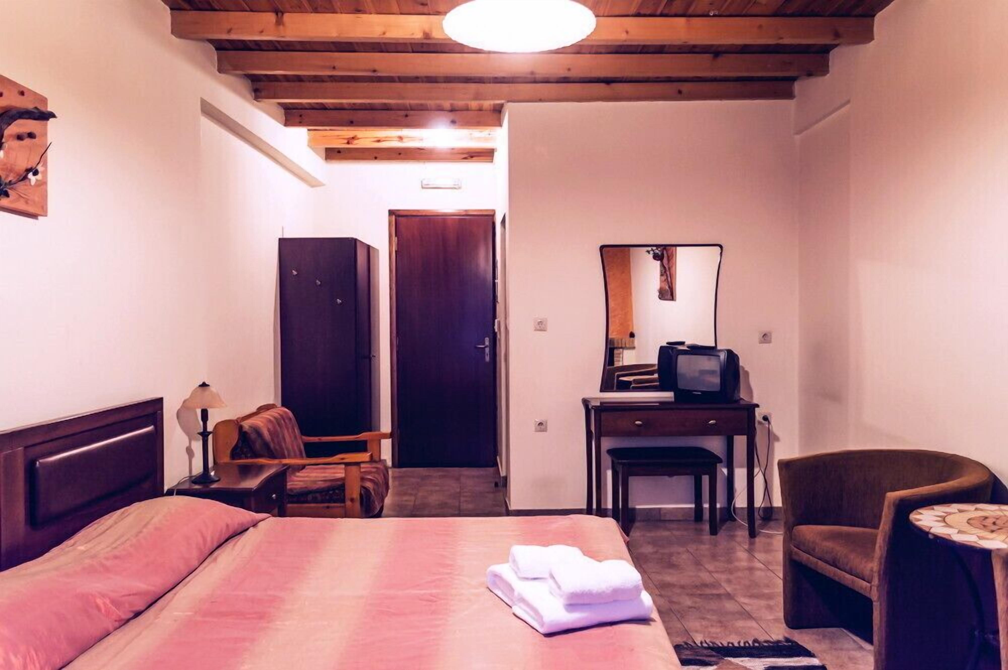 Una habitación de hotel con una cama, un escritorio con televisor, una silla y una pequeña mesa.