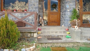 A stone building with a wooden door, a small porch, and a stone wall. - Guesthouse Teloni (Gortynia)
