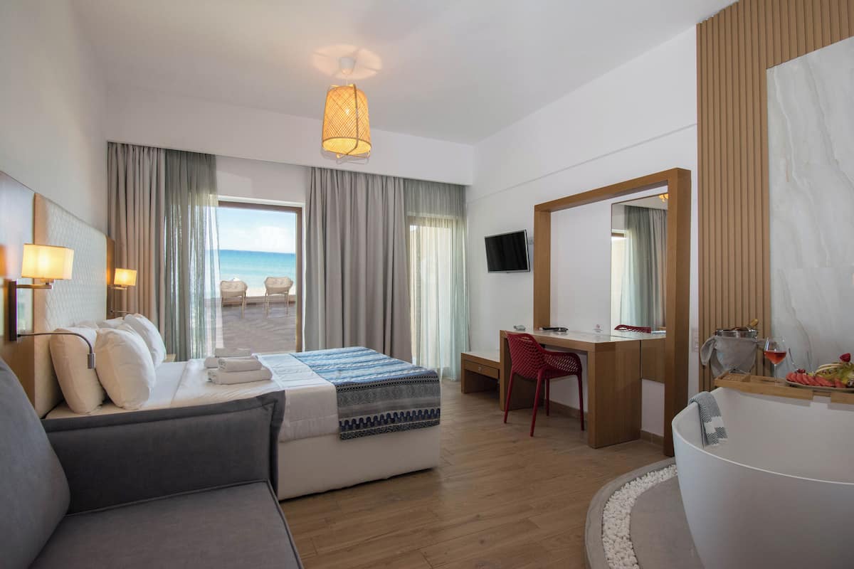 Habitación de hotel con cama, escritorio, silla, un espejo grande y vista al mar.