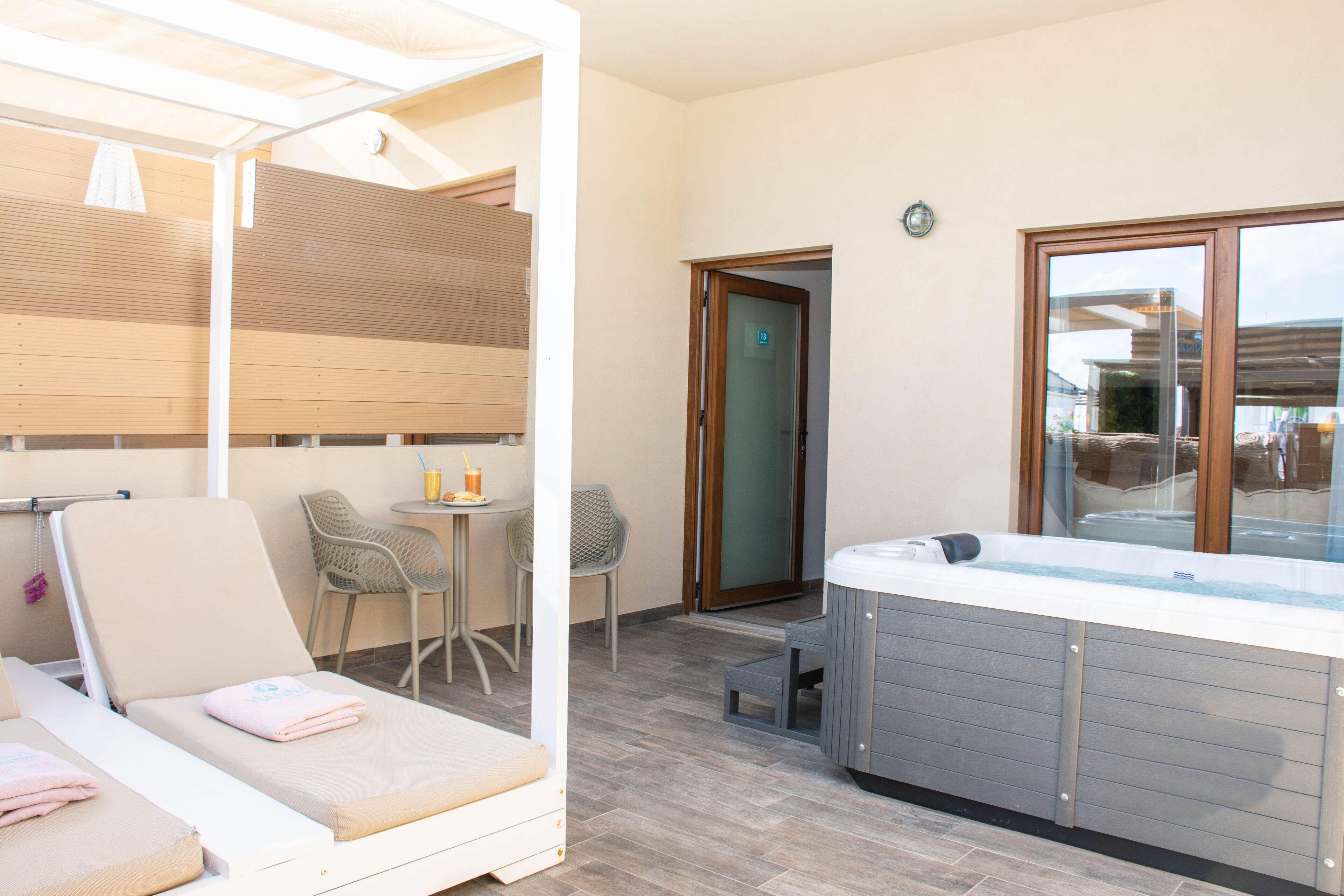 Une chambre moderne dotée d’un jacuzzi, de deux fauteuils, d’une petite table avec des chaises et d’une porte donnant sur l’extérieur.