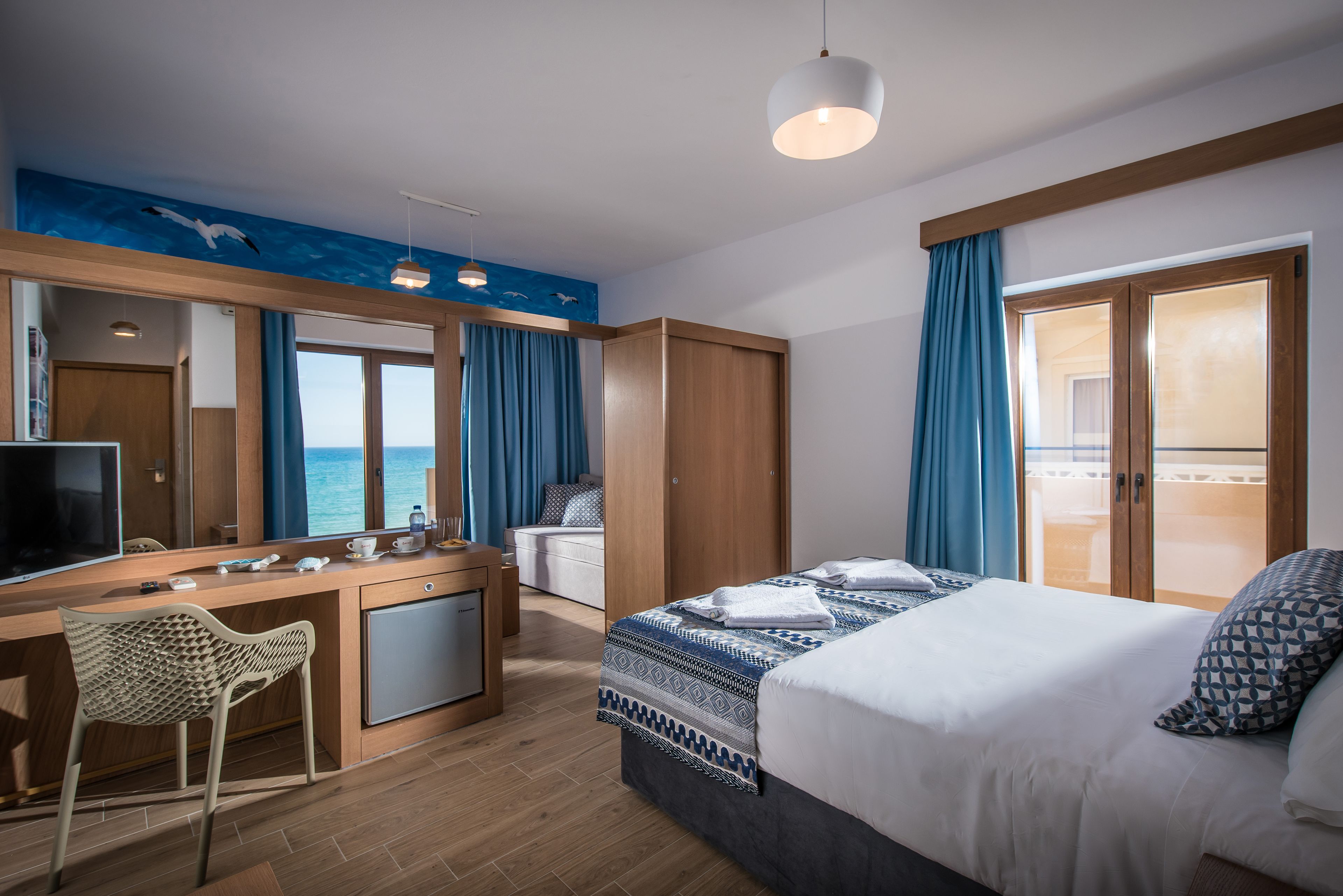 Une chambre d’hôtel avec un lit, un bureau, une chaise et une grande fenêtre avec des rideaux.