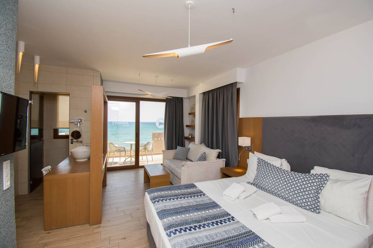 Una habitación de hotel con cama, sofá, escritorio y vista al mar.