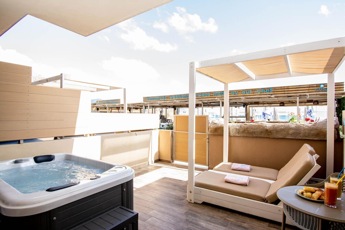 Una terraza en la azotea con jacuzzi, un sillón de tomar el sol y una mesa con una bebida.