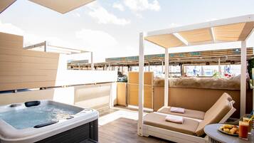 Eine Dachterrasse mit Whirlpool, Liegebereich und Blick auf die Skyline der Stadt.