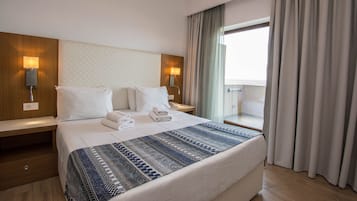 Habitació d'hotel amb un llit gran, dues taules de nit, una finestra amb cortines i vista a l'exterior.