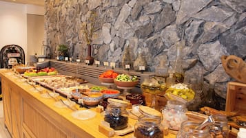 Un buffet proposant une variété de plats et d’accompagnements, le tout disposé devant un mur en pierre.