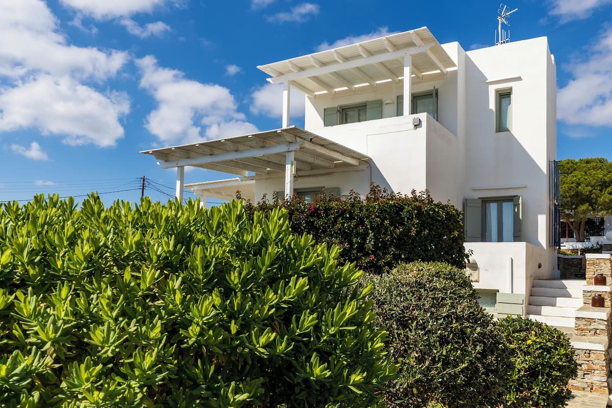 Un edificio moderno de color blanco con techo plano, un porche cubierto y una escalera de piedra que conduce a la entrada.