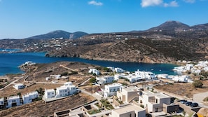 A coastal village with white buildings, a clear blue sea, and mountains in the background. - Maisons a la Plage (Sifnos)