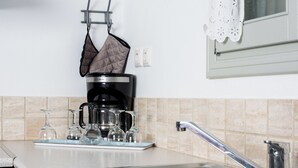 A kitchen with a stainless steel sink, a coffee maker, and glassware on the counter. - Maisons a la Plage (Sifnos)